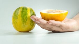 Cetriolo Limone maturo intero su un tavolo ed uno diviso a metà su una mano, di forma sferica e colore giallo brillante